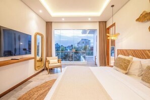 A modern hotel room with a large bed, a sitting area with a chair, a TV, and a balcony with a city view.