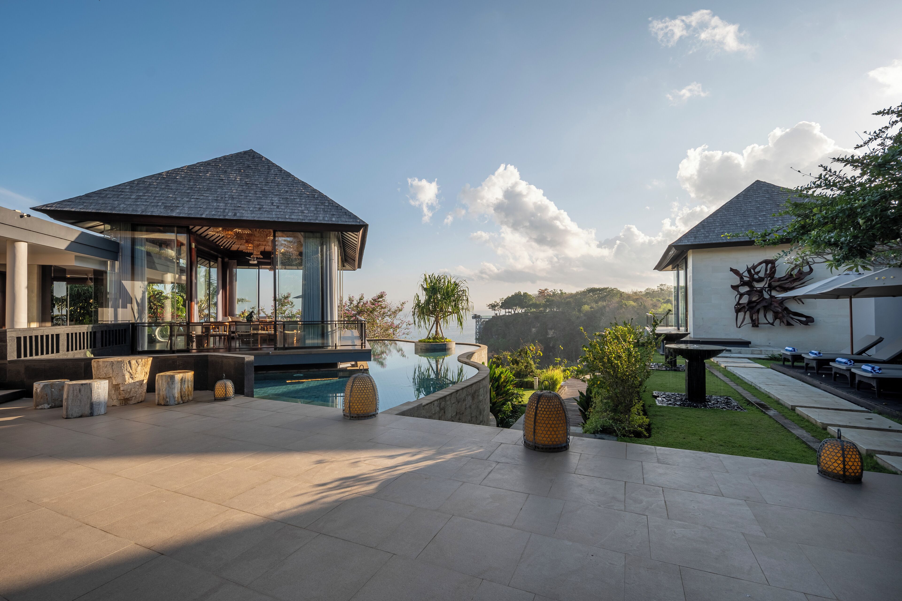 A modern resort with a swimming pool, outdoor seating, and a view of the surrounding landscape.