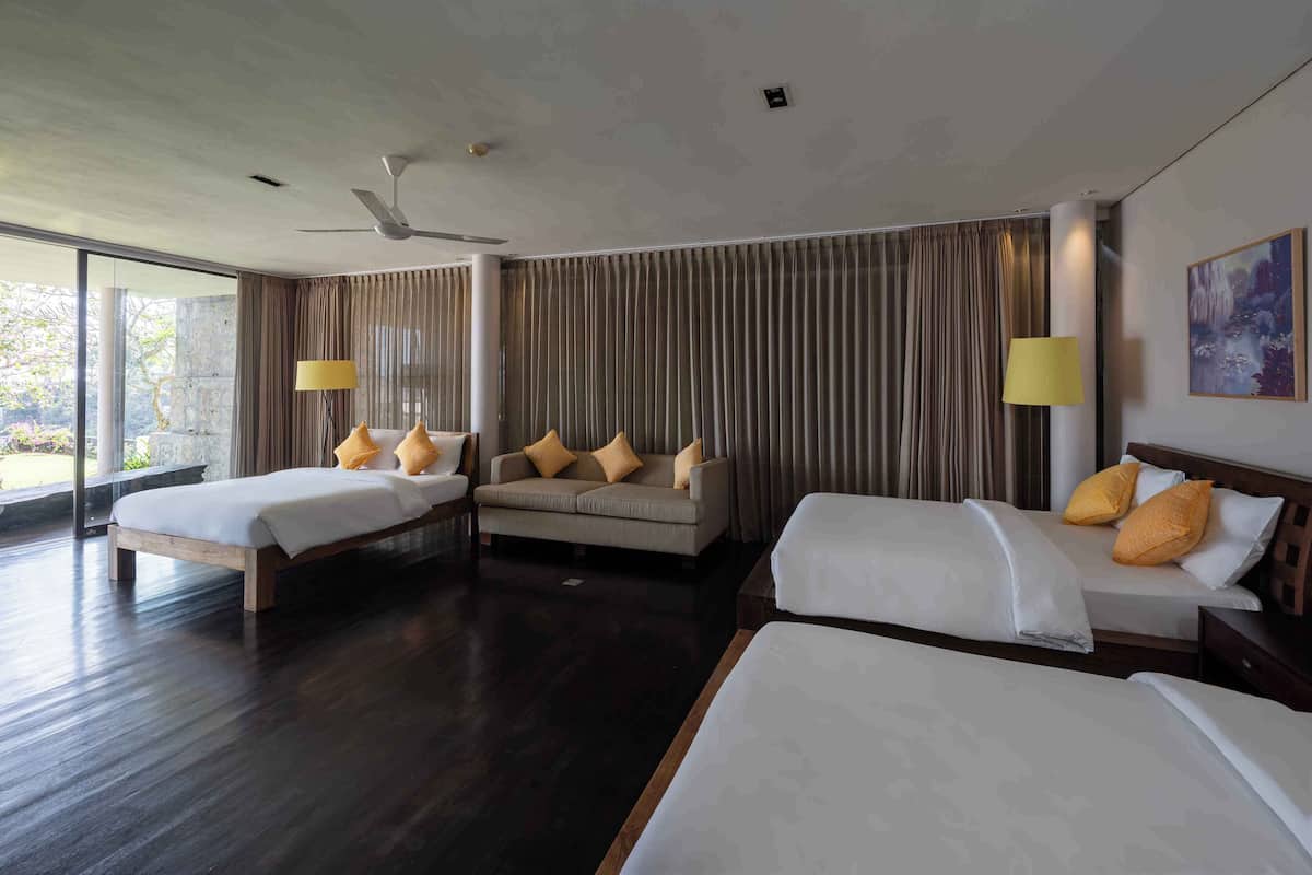 A hotel room with two beds, a sofa, and a large window.
