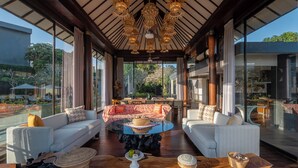 A spacious living area with a round glass coffee table, two sofas, and a dining table with chairs. - By The Cliff Bali Villa (Jimbaran)