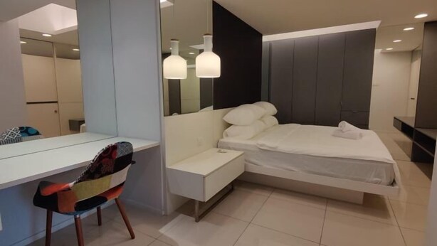Une chambre à coucher moderne avec un lit, une table de chevet, une chaise et un grand miroir.