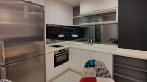 Une cuisine moderne dotée d’appareils électroménagers en acier inoxydable, de meubles blancs et d’un plan de travail noir.