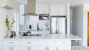 Eine moderne Küche mit weißen Schränken, einem Edelstahl-Kühlschrank, einer Mikrowelle und einer großen Kochinsel mit Barhocker.