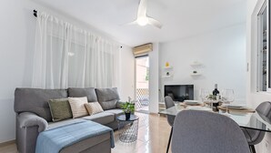 Een moderne woonkamer met een grijze bank, een salontafel en een eetgedeelte met een glazen tafel en stoelen.