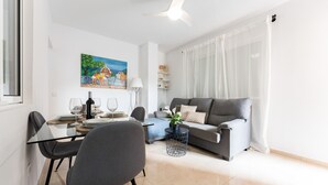 Een moderne woonkamer met een eethoek, met een bank, een salontafel en een schilderij aan de muur.
