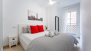 Een slaapkamer met een bed, nachtkastje, raam met uitzicht en plafondventilator.