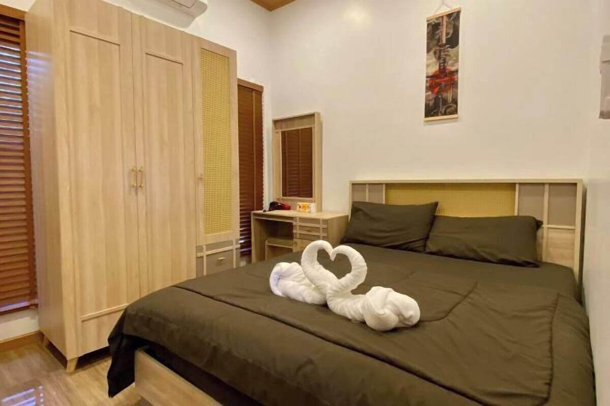 A bedroom with a bed, a desk, a wardrobe, and a painting on the wall.