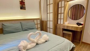 Una habitación de hotel con una cama, cabecera de madera, mesita de noche con espejo y una obra de arte colgada en la pared.
