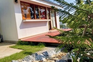 A building with a red roof, a stone pathway, and a small garden area. - Taka Onzen (Kaeng Khoi)