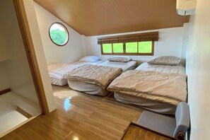 A compact bedroom with two beds, a small window, and a wooden floor. - Taka Onzen (Kaeng Khoi)