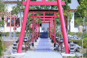 A pathway leading to a traditional Japanese structure with a red torii gate. - Taka Onzen (Kaeng Khoi)