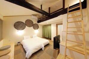 Een slaapkamer met een groot bed, een televisie en een houten trap.