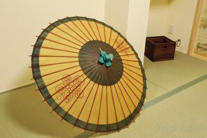 A traditional Japanese room with tatami flooring, a wooden floor lamp, and a small wooden cabinet. - Kamado and Tsuboyunoyado Osaka Minami (Osaka)