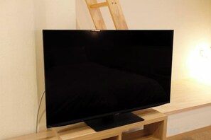 A flat-screen TV on a wooden stand against a wall. - Kamado and Tsuboyunoyado Osaka Minami (Osaka)