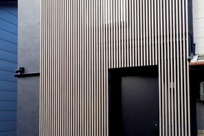 A building facade with vertical lines and a black door. - Kamado and Tsuboyunoyado Osaka Minami (Osaka)
