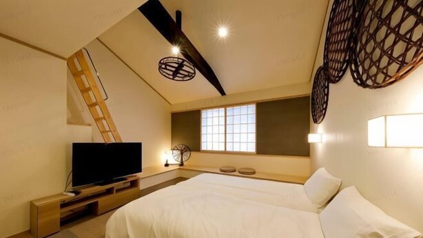 Un dormitorio con cama, televisión, escalera y ventana con luz natural.