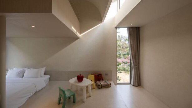 A modern hotel room with a bed, a small table with a red object, a green chair, and a suitcase. - Number Three Pool Villa Khaoyai (Pak Chong)
