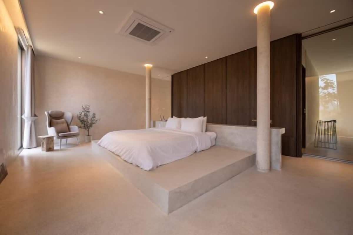 A modern bedroom with a large bed, a chair, and a small table.
