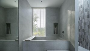 A modern bathroom with a large bathtub, a window, and a tiled wall. - Number Three Pool Villa Khaoyai (Pak Chong)