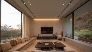 A modern living room with a large sofa, a coffee table, and a TV mounted on the wall. - Number Three Pool Villa Khaoyai (Pak Chong)