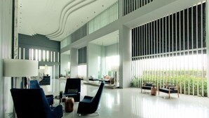 A spacious lobby with modern furniture, large windows, and a high ceiling.