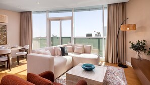 A modern living room with a sofa, coffee table, and a view of the city through large windows. - Dazzling Downtown Retreat w Panoramic City Views (Dubai)
