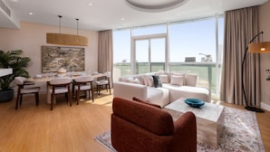 A modern living room with a dining area, large windows, and a city view. - Dazzling Downtown Retreat w Panoramic City Views (Dubai)