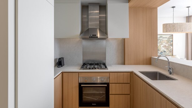 A modern kitchen with a stainless steel range hood, a built-in oven, and a sink. - Dazzling Downtown Retreat w Panoramic City Views (Dubai)