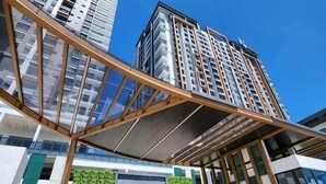 A modern hotel with a prominent entrance, a glass facade, and a green vertical garden. - Urban Retreat @ K Avenue • Pool • Paid Parking (Donggongon)