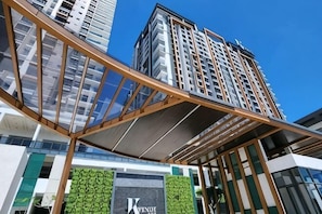 A modern hotel with a prominent entrance, a glass facade, and a green vertical garden.