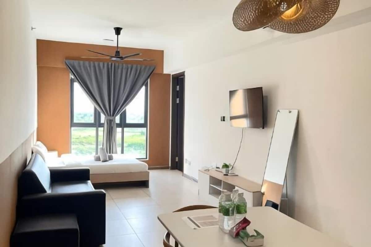 A modern hotel room with a sofa, dining table, TV, and large windows.