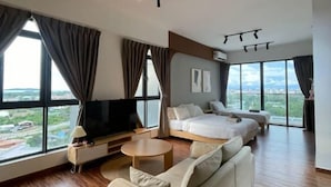 A modern hotel room with a large bed, a sofa, a TV, and a dining table. - Urban Retreat @ K Avenue • Pool • Paid Parking (Donggongon)