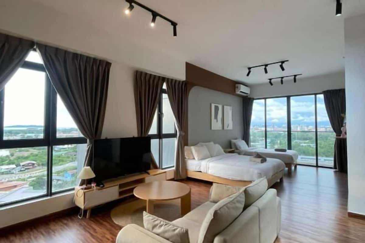 A modern hotel room with a large bed, a sofa, a TV, and a dining table.
