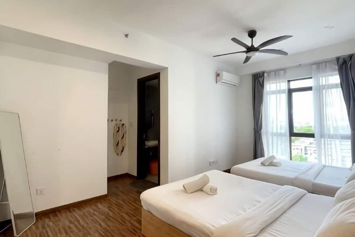 A hotel room with two beds, a ceiling fan, a window with curtains, and a door leading to another room.