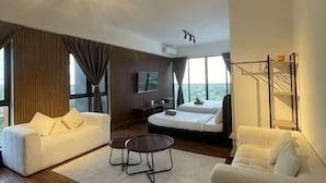 A modern hotel room with a large bed, two white sofas, a coffee table, and a TV. - Urban Retreat @ K Avenue • Pool • Paid Parking (Donggongon)