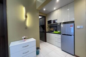 A compact kitchen with white cabinets, a stainless steel refrigerator, and a small countertop. - Urban Retreat @ K Avenue • Pool • Paid Parking (Donggongon)