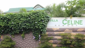 A sign for Villa Celine Resort with a green leafy wall and a patterned log design. - Villa Celine Laguna (Laguna)