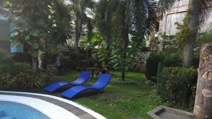 A pool area with blue lounge chairs and a stone wall. - Villa Celine Laguna (Laguna)