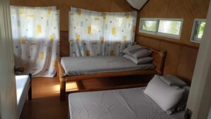 A compact room with two beds, wooden paneling, and a window with a view. - Villa Celine Laguna (Laguna)