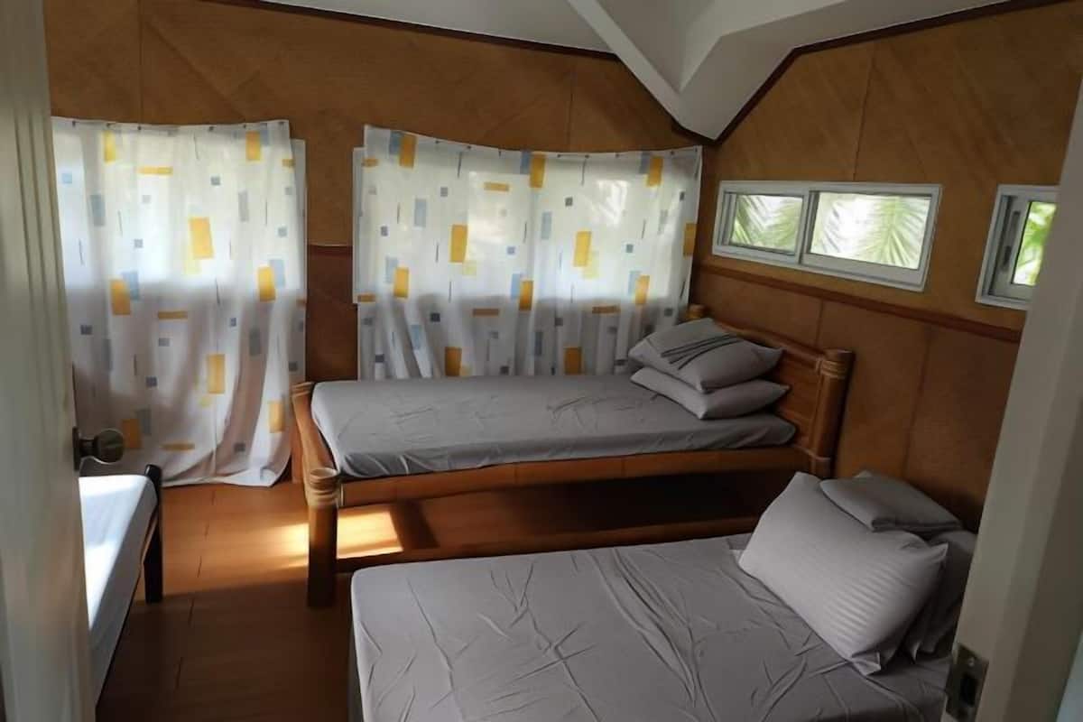 A compact room with two beds, wooden paneling, and a window with a view.