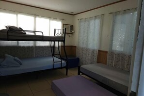 A dormitory room with bunk beds, a small table, and a window with curtains. - Villa Celine Bay Laguna (Laguna)