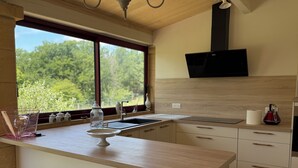 Eine moderne Küche mit großem Fenster, Holzschränken, integriertem Mikrowellenherd und einer Spüle.