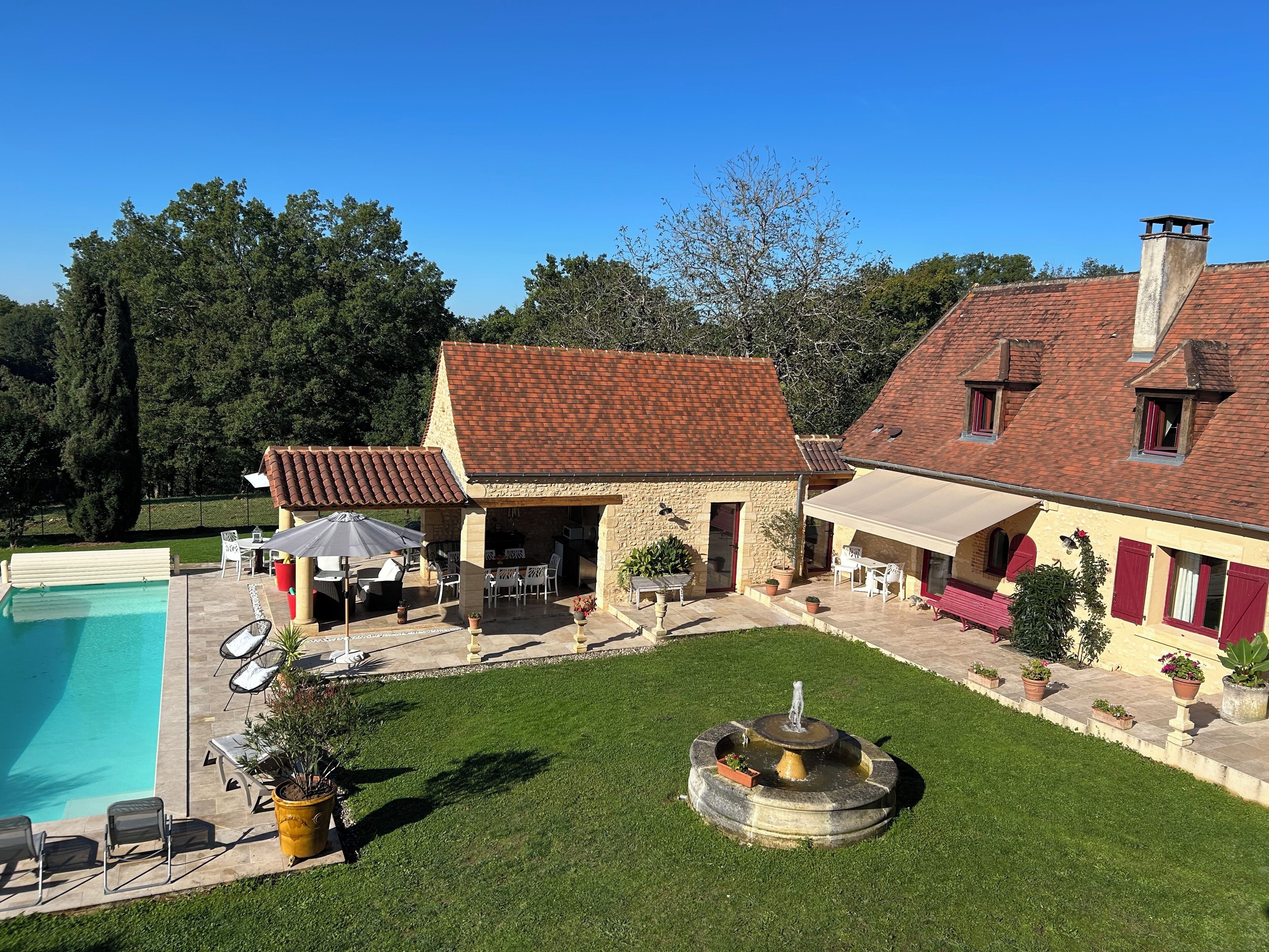 Une villa dotée d’une piscine, d’un espace salon extérieur et d’une fontaine.