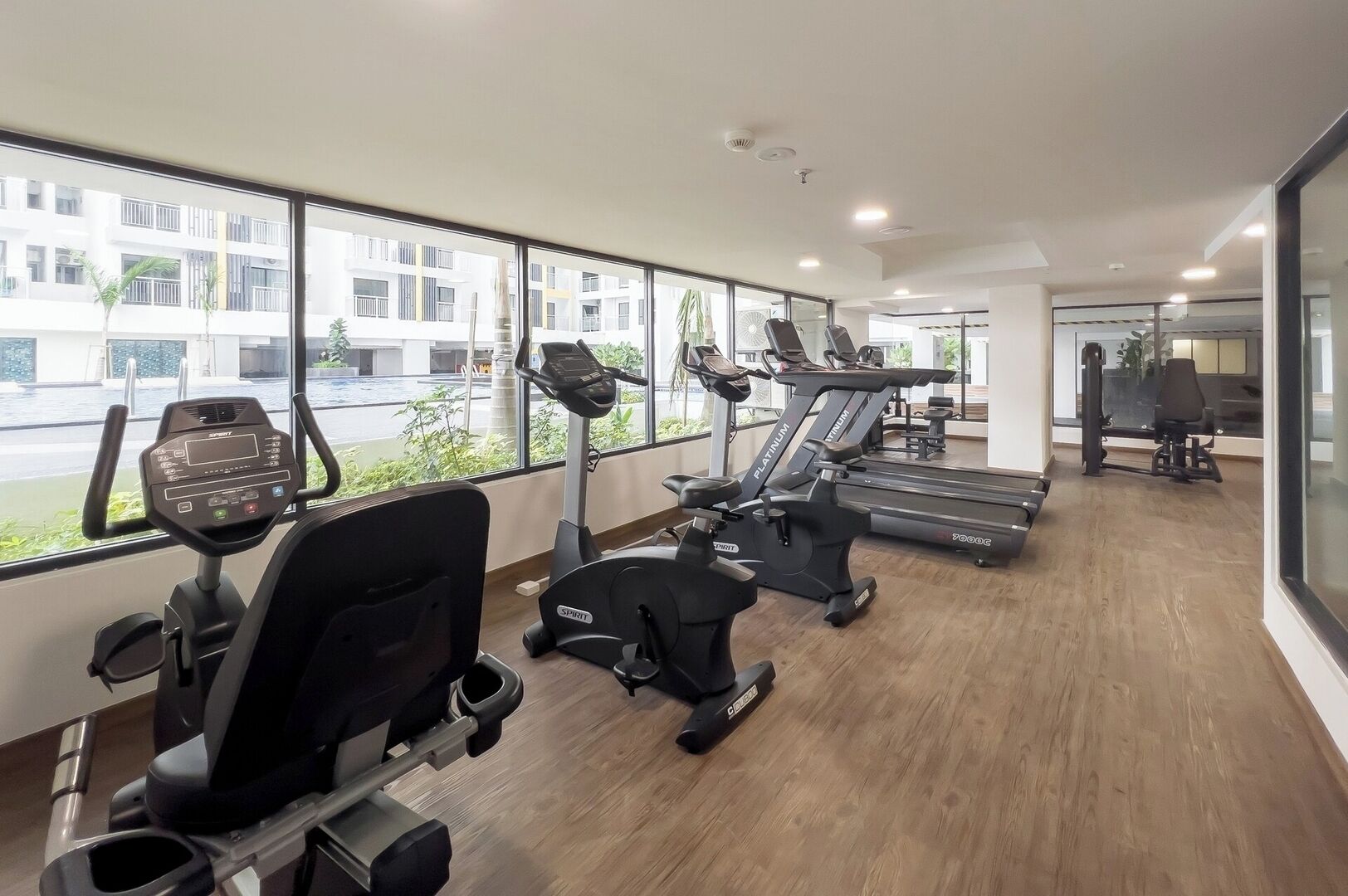 Un gimnasio con equipo de ejercicio, ventanas amplias y vistas al exterior.