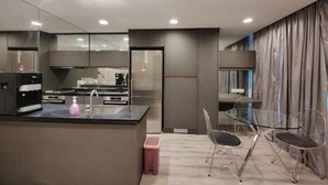 Une cuisine moderne dotée d’un îlot central, d’appareils électroménagers en acier inoxydable et d’une table à manger en verre, assortie de chaises à structure métallique.