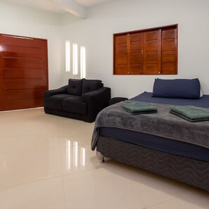 A bedroom with a bed, a sofa, and a wooden wardrobe. - Amazon House with Pool, Pool Table, BBQ, 5 min from the Beach (Macapá)