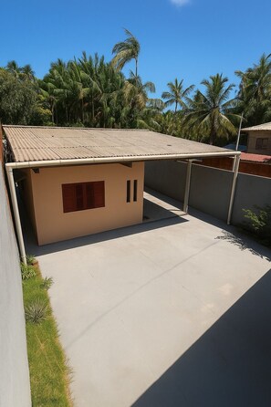 A single-story building with a flat roof, a small attached structure with a red door, and a concrete patio area. - Amazon House with Pool, Pool Table, BBQ, 5 min from the Beach (Macapá)