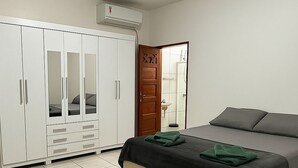 A bedroom with a bed, a wardrobe, and a door leading to a bathroom. - Amazon House with Pool, Pool Table, BBQ, 5 min from the Beach (Macapá)