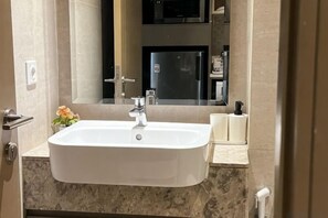A bathroom with a white sink, a mirror, and a towel rack.