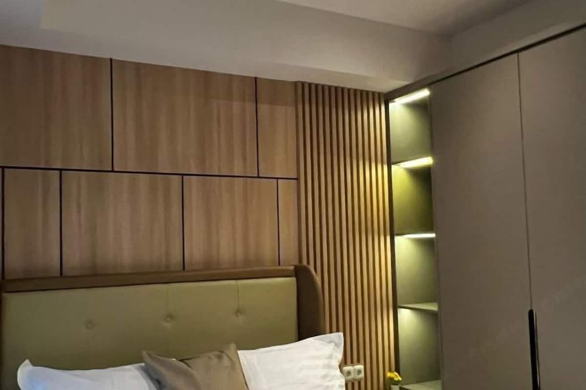 A modern bedroom with a bed, built-in wooden paneling, and a built-in shelving unit.